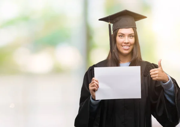 笑顔の サイン 優秀な兆候を親指をやって幸せな卒業証書用紙を持って若いヒスパニック女性着て卒業制服 — ストック写真