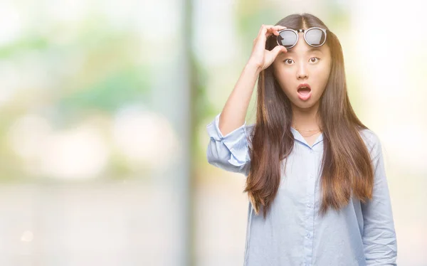 年轻的亚洲妇女戴着太阳镜在孤立的背景下害怕和震惊惊讶的表情 恐惧和兴奋的脸 — 图库照片