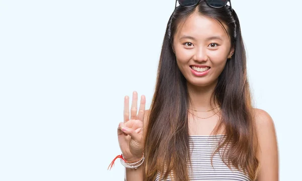 年轻的亚洲妇女戴着太阳镜在孤立的背景显示和指向手指三 而微笑着自信和快乐 — 图库照片