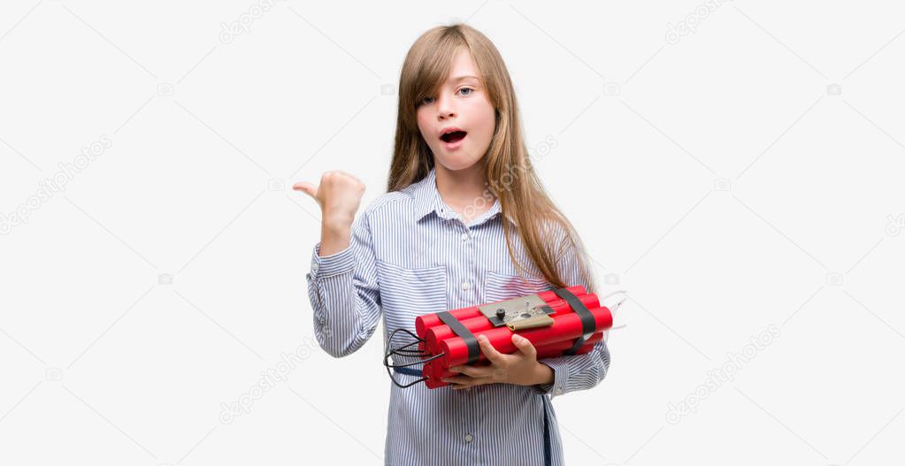 Young blonde child holding dynamite bomb pointing with hand and finger up with happy face smiling