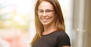 Orta yaş kadın siyah gömlek ve gözlük kendinden emin ve mutlu bir büyük doğal gülümseme davet ile girmek için