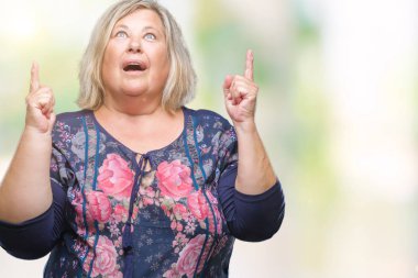 Kıdemli artı izole arka plan üzerinde beyaz kadın hayrete ve yukarıya bakıp parmakları ile işaret şaşırttı ve silah kaldırdı boyutu.