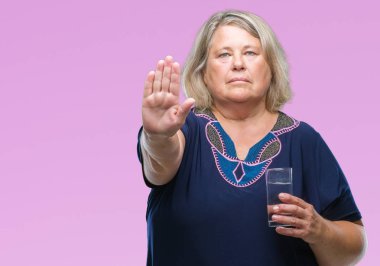 Kıdemli artı boyutu ile arka plan beyaz kadın üzerinde bardak su içme izole dur işareti ile ciddi ve kendine güvenen ifade, savunma hareketi yaparken el açmak