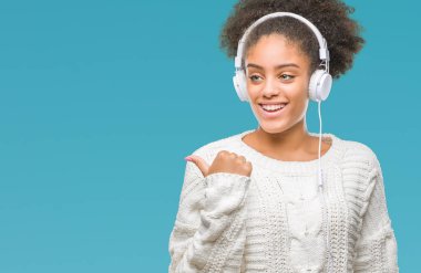 İşaret ve başparmak kadar mutlu yüz gülümseyen tarafı ile gösteren izole arka plan üzerinde kulaklık giyen genç afro Amerikan kadın