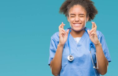 Genç afro Amerikalı doktor kadın geçiş parmakları umut ve gözler gülümseyen izole arka plan yüzünden kapalı. Şans ve batıl kavramı.