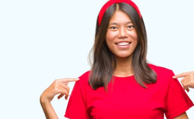 Yüzünde gülümseme ile kendinden emin görünüyorsun, kendini gururlu ve mutlu parmakları ile işaret izole arka plan üzerinde Genç Asyalı kadın.