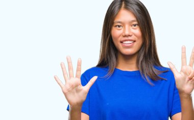 Genç Asyalı kadın gösterilen ve parmakları ile işaret izole arka plan üzerinde kendinden emin ve mutlu gülümseyerek süre sekiz numara.