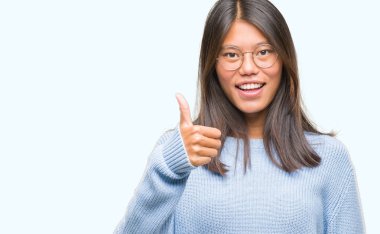 Genç Asyalı kadın hareketi el ile mutlu yaşasın yapıyor izole arka plan üzerinde kış kazak giyiyor. Kameraya bakarak başarı gösteren ile ifade onaylama.