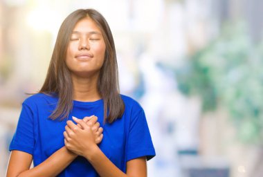 Genç Asyalı kadın ile gülümseyen izole arka plan üzerinde kapalı gözler ve yüzünde minnettar jest ile göğüs üzerinde eller. Sağlık kavramı.