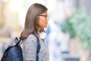 İzole arka tarafına, seyir üzerinde kulaklık ve sırt çantası giyen genç Asyalı öğrenci kadın dinlenmek doğal yüz emin gülümseme ile pozuyla profili.