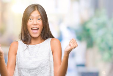 Genç Asyalı kadın kutluyor izole arka plan üzerinde şaşırttı ve başarı için kaldırdı kollarını açarak hayret ve gözleri açık. Kazanan kavramı.