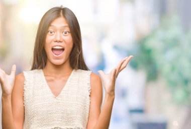 Genç Asyalı kadın deli kutluyor ve silah ile başarı için heyecanlı çığlık kaldırdı ve açık gözleri hayret izole arka plan üzerinde. Kazanan kavramı