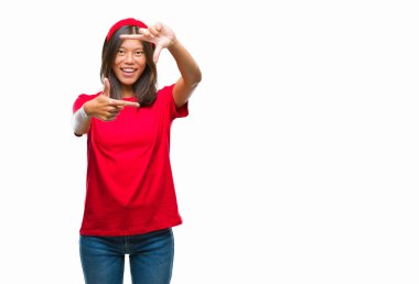 Genç Asyalı kadın elle yapma çerçeve ve parmakları ile mutlu yüz gülümseyen izole arka plan üzerinde. Yaratıcılık ve Fotoğrafçılık kavramı.