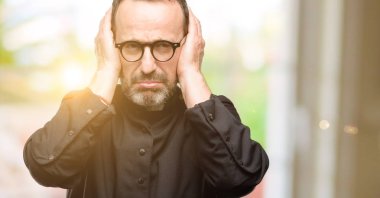 Rahip din adamı kapsayan kulaklar, gürültü rahatsız edici görmezden fişler kulakları işitme ses önlemek için. Gürültülü müzik bir sorundur.