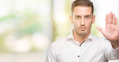 Yakışıklı genç iş adamı açık eliyle dur işareti ile ciddi ve kendine güvenen ifade, savunma hareketi yapıyor