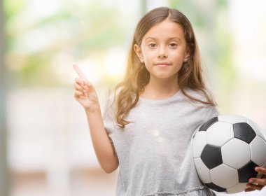 Esmer Latin kız futbol futbol topu çok mutlu el ve parmak ile tarafına işaret tutan