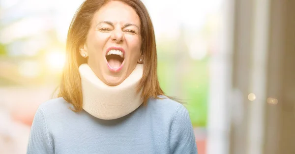 Injured woman wearing neck brace collar stressful, terrified in panic, shouting exasperated and frustrated. Unpleasant gesture. Annoying work drives me crazy