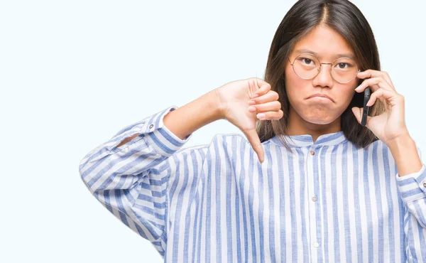 怒った顔 ダウン親指で嫌悪感を示すマイナス記号 拒絶反応の概念と分離された背景に電話で話す若いアジア女性 — ストック写真
