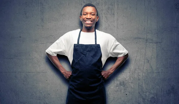 African man shop owner wearing apron confident and happy with a big natural smile laughing