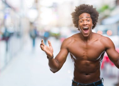 Afro Amerikalı gömleksiz adam çıplak vücut üzerinde gösterilen çılgın kutlama arka plan izole ve silah ile başarı için yükseltilmiş ve açık gözleri heyecanlı çığlık hayrete düşürdü. Kazanan kavramı