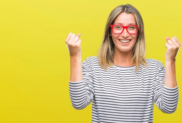 İzole arka plan üzerinde kutluyor gözlük takan genç güzel kadın şaşırttı ve silah ile başarı için yükseltilmiş ve açık gözler hayrete düşürdü. Kazanan kavramı.
