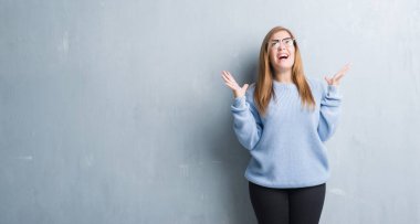 Gri grunge duvar çılgın ve kızgın bağırarak ve agresif ifade ve silah kaldırdı bağırmaya gözlüklü Genç Yetişkin kadın. Hayal kırıklığı kavramı.