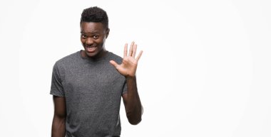 Gösterilen ve parmakları ile işaret gri t-shirt giyen genç Afro-Amerikan adam kendinden emin ve mutlu gülümseyerek süre beş numara.