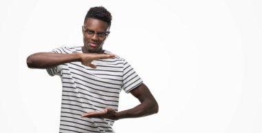 Gözlük ve lacivert t-shirt eller eller büyük gösterilen ve büyük boy işareti, ölçü birimi sembolü ile giyen genç Afro-Amerikan adam. Kameraya bakarak gülümsüyordu. Ölçüm kavramı.