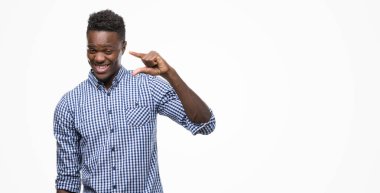 Genç Afro-Amerikan adam mavi tişört giyiyor gülümseyen ve boyutu işi el ile kendinden emin eller parmakları ile seyir ve fotoğraf makinesi oturum açın. Ölçü kavramı.