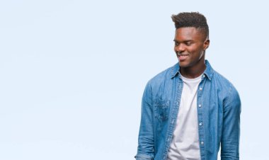 Afrikalı-Amerikalı genç uzak tarafına yüzünde, doğal ifade gülümseme ile seyir izole arka plan üzerinde. Kendine güvenen gülüyor.