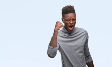 Afrikalı-Amerikalı genç izole arka plan öfkeli ve sinirli sinirli ve öfke ile bağırarak süre öfkeli yumruk yükselterek üzerinde. Öfke ve agresif kavramı.