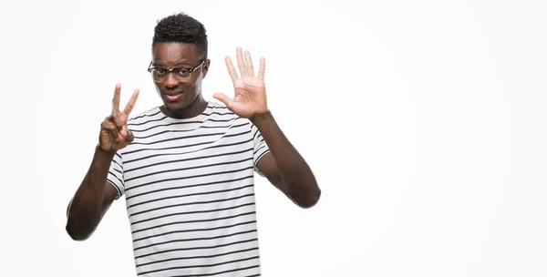 メガネと指で上向きの表示とネイビーの シャツを着て若いアフリカ系アメリカ人の数は自信を持って 幸せな笑みを浮かべている間 — ストック写真