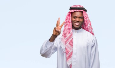 Geleneksel keffiyeh gösterilen ve parmakları ile işaret izole arka plan üzerinde giyen genç Arapça Afrika adam kendinden emin ve mutlu gülümseyerek iken üçüncü.