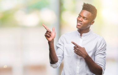 Gülümseyen ve iki elleri ve parmakları ile tarafına işaret kamera bakarak izole arka plan üzerinde genç Afro-Amerikan adam.