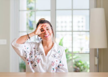 Genç kadın evde gülümseyen, parmakları ile mutlu yüz üzerinden seyir göz el ile ok jest yapıyor.