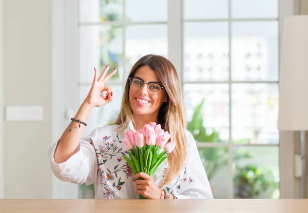 Jovem Mulher Casa Segurando Flores Tulipas Rosa Fazendo Sinal Com — Fotografia de Stock