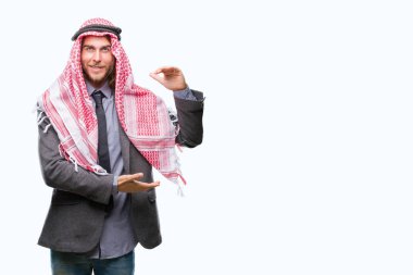 Genç yakışıklı Arap adam uzun saçlı ile büyük ve büyük boy işaret, ölçü birimi sembol gösteren el eller izole arka plan üzerinde keffiyeh giyiyor. Kameraya bakarak gülümsüyordu. Ölçüm kavramı.