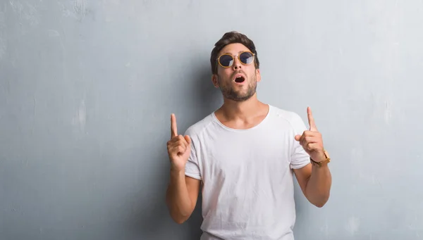 Schöner Junger Mann Über Grauer Grunge Wand Mit Sonnenbrille Staunend — Stockfoto