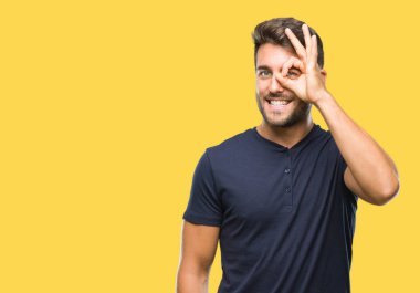 Genç yakışıklı adam gülümsüyor, parmakları ile mutlu yüz üzerinden seyir göz el ile ok jest yapıyor izole arka plan üzerinde.