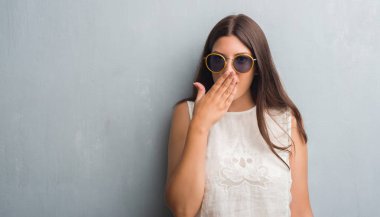 Grunge gri duvar giyen retro güneş gözlüğü genç esmer kadın kapak ağız elle hata, korku, sessizlik içinde gizli kavramı korkmuş ifade için utanç ile şok