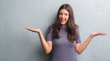 Grunge genç esmer kadın gri duvar çok mutlu ve heyecanlı, kocaman bir gülümseme ile çığlık ve ellerini kaldırdı kazanan ifade kutluyor zafer