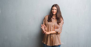 Genç esmer kadın grunge gri duvar yüzünden tiksinti ifadesi, memnun ve korkulu tiksinti yüz yapıyorsun çünkü nefret tepki. Elleriyle kaldırdı. Sinir bozucu kavramı.