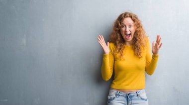 Gri grunge genç Kızıl saçlı kadın kutluyor deli duvar ve çığlık kaldırdı ve açık gözleri hayret silah ile başarı için heyecanlı. Kazanan kavramı