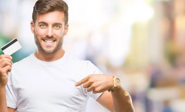 Jovem Bonito Homem Segurando Cartão Crédito Sobre Fundo Isolado Com — Fotografia de Stock