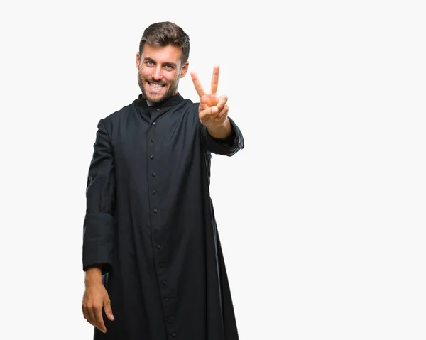 勝利のサインをやって指を表示するカメラを笑みを浮かべて隔離された背景に男は若いカトリック教のキリスト教の司祭 — ストック写真