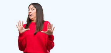 Şokta bağırarak kırmızı kazaklı korkuyor ve korku ifade dur hareketi el ile ile dehşete giyen genç güzel İspanyol. Panik kavramı.