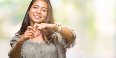 Genç güzel Arap kadın kalp simgesi ve elleriyle şekil gösterilen aşık gülümseyen izole arka plan yüzünden. Romantik kavramı.