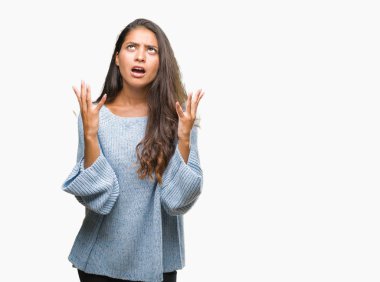 Üzerinde kış kazak giyen genç güzel Arap kadın arka plan deli izole ve deli bağırarak ve agresif ifade ve silah kaldırdı bağırıyor. Hayal kırıklığı kavramı.