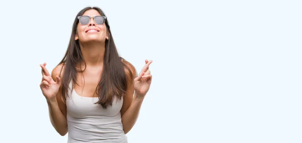 Joven Hermosa Hispana Con Gafas Sol Sonriendo Cruzando Los Dedos — Foto de Stock