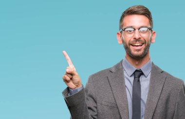 Kameraya bakarak yan el ve parmak ile işaret eden genç yakışıklı iş adamı yüzünde kocaman bir gülümseme ile izole arka plan üzerinde.